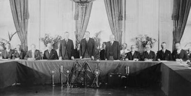 Pactul Kellogg-Briand (27 august 1928): Calvin Coolidge, Herbert Hoover și Frank B. Kellogg, (în picioare), alături de reprezentanții guvernelor care au ratificat "Tratatul pentru renunțare la război" (Pactul Kellogg-Briand), în "Camera de răsărit" a Casei Albe - foto preluat de pe ro.wikipedia.org