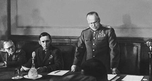 Actul capitulării Germaniei (07 - 08 mai 1945) - Mareșalul Uniunii Sovietice Gheorghi Jukov citind actul capitulării Germaniei la Cartierul său General din Berlin. La dreapta sa se află Mareșalul Forțelor Aeriene al Regatului Unit, Arthur Tedder - foto preluat de pe ro.wikipedia.org