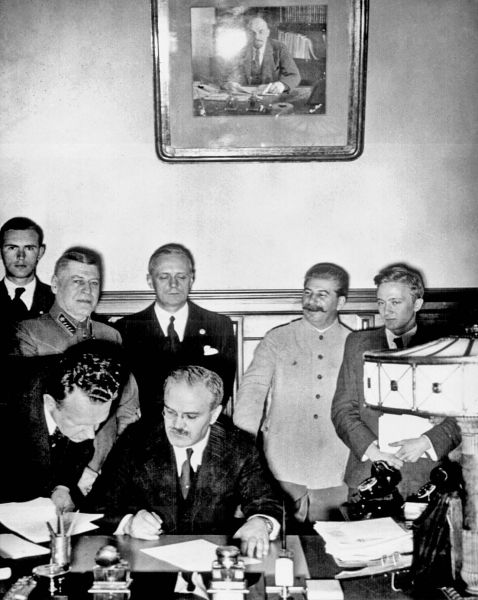 Ministrul sovietic de externe Viaceslav Molotov semnând Pactul de neagresiune sovieto-german. În spatele său se văd ministrul de externe german Joachim von Ribbentrop (stânga) și primul ministru sovietic Iosif Vissarionovici Stalin. - foto preluat de pe istoria.md