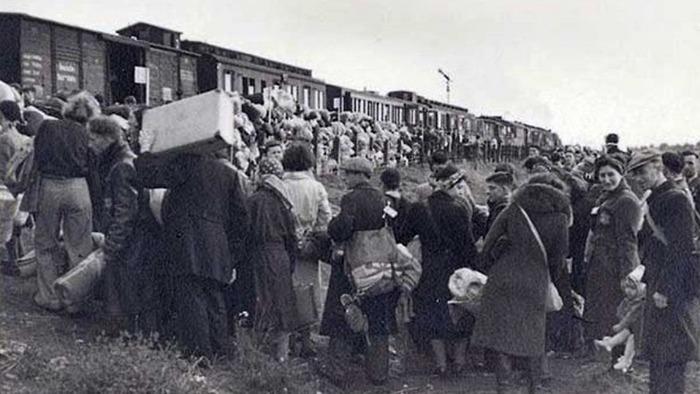 Grupuri de deportați basarabeni adunați lângă un tren de marfă în timpul deportărilor sovietice din iunie 1941.